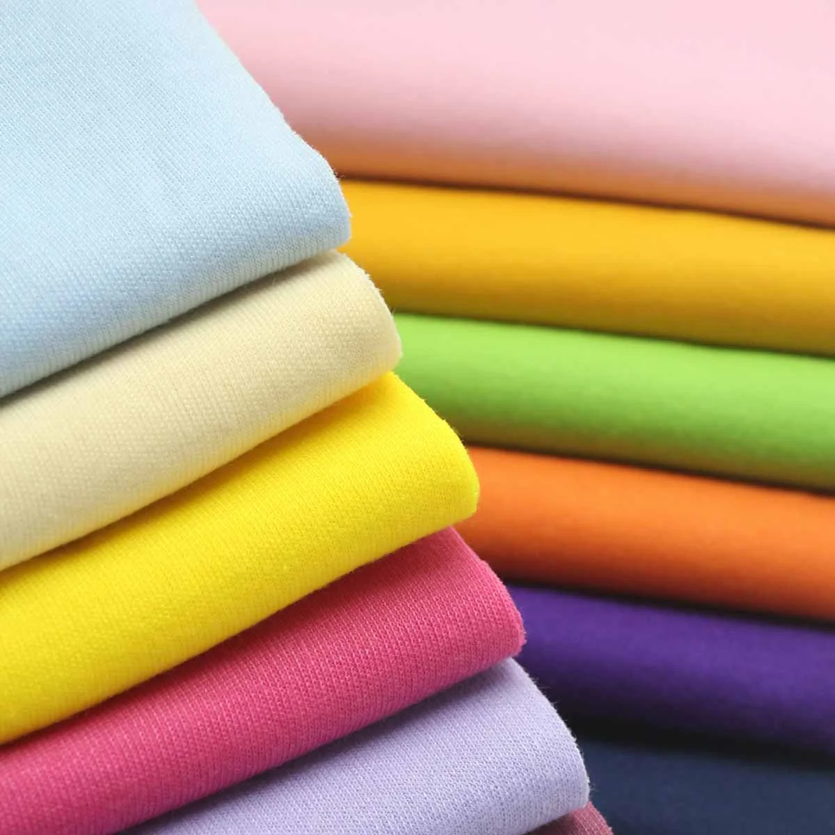 Gestapelte Baumwollstoffe in Hellblau, Beige, Gelb, Grün, Orange, Pink und Violett
