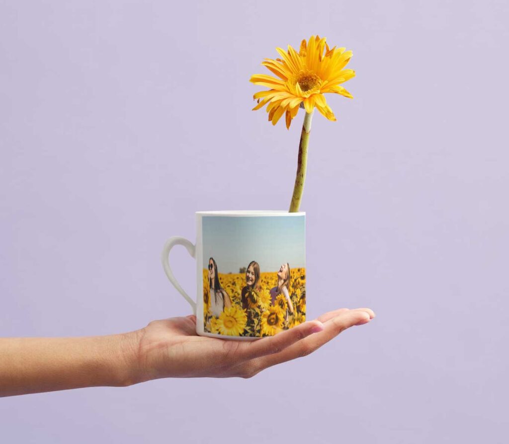 Weiße Tasse bedruckt mit einem Foto von Freunden. In der Tasse steht eine Blume, perfekt zum Verschenken.